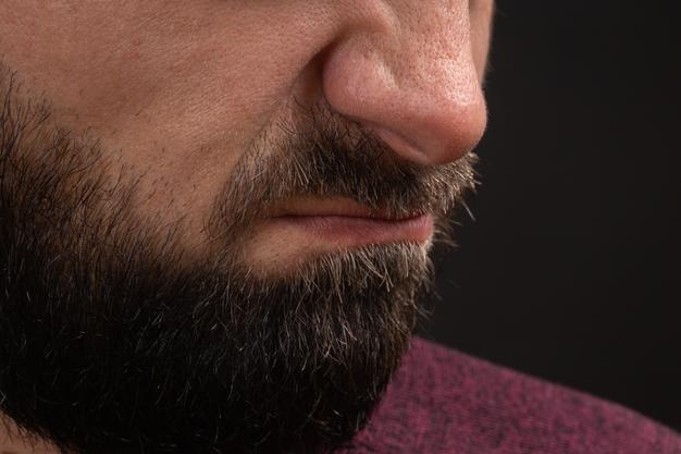 Wrinkled grimace of danger closeup on face and lips of young unrecognizable man with black beard and...